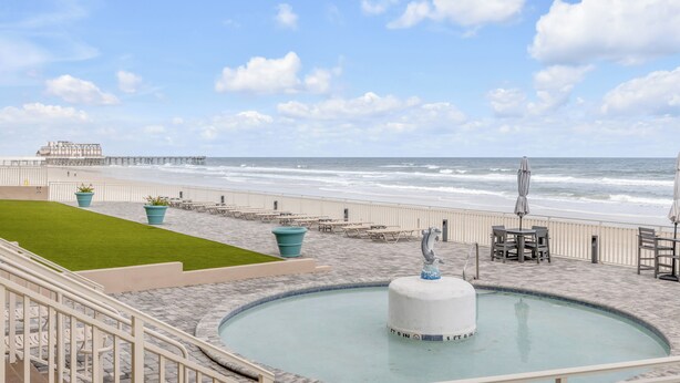 Area piscina fronte mare con fontana, posti a sedere e vista sull'oceano.