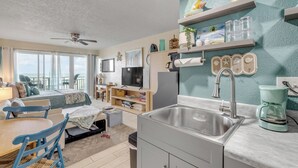Un ambiente compatto con angolo cottura, zona pranzo e camera da letto con vista.