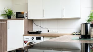Uma cozinha moderna com armários brancos, micro-ondas, fogão e cafeteira.