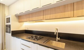 Una cucina moderna con mobili bianchi, un piano di lavoro nero e elettrodomestici in acciaio inossidabile.