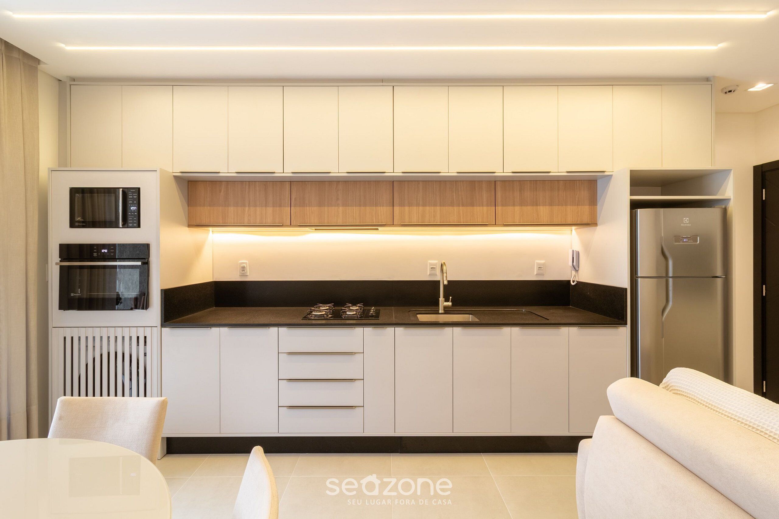 A modern kitchen with built-in appliances, a dining area, and a sofa.