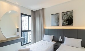 Una camera d'albergo moderna con un letto, comodini, uno specchio grande e opere d'arte alle pareti.