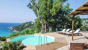 A poolside area with lounge chairs, a wooden deck, and a view of the sea. - Seaview villa, design, comfort and privacy, pool, sandy, white beach 5 min walk (Sardegna)
