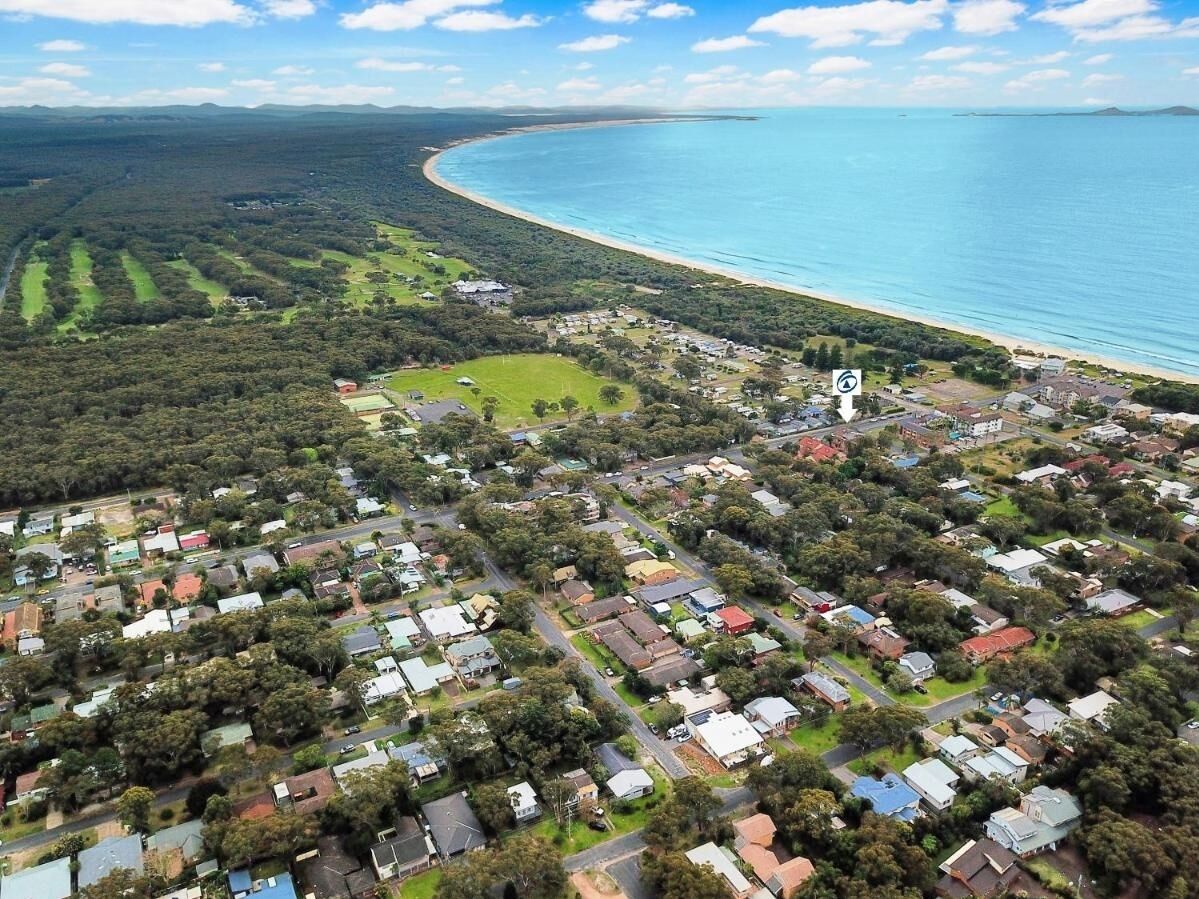 Luftaufnahme einer Küstenwohngegend mit Häusern, Straßen und einem Strand.