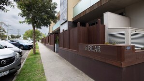 A building with a sign reading "6 BEAR" and a parking area with cars.