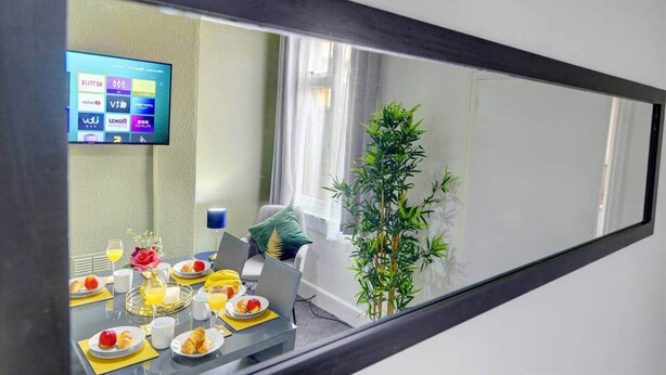 Habitación de hotel con una mesa lista para el desayuno, un televisor en la pared y una planta en maceta.