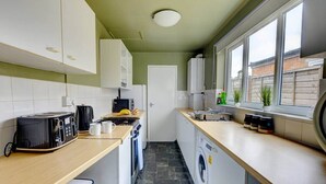 Una cocina compacta con tostadora, microondas, lavabo y lavadora.