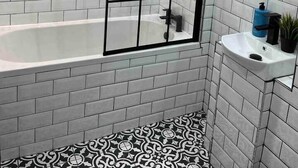 Un bagno moderno con piastrelle bianche a metro, cabina doccia in vetro, vasca da bagno bianca e pavimento a motivi bianchi e neri.