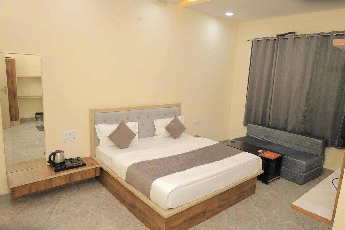 A hotel room with a bed, bedside table, and a small seating area.