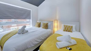 Een hotelkamer met twee bedden, een raam, een lamp en uitzicht op gebouwen.