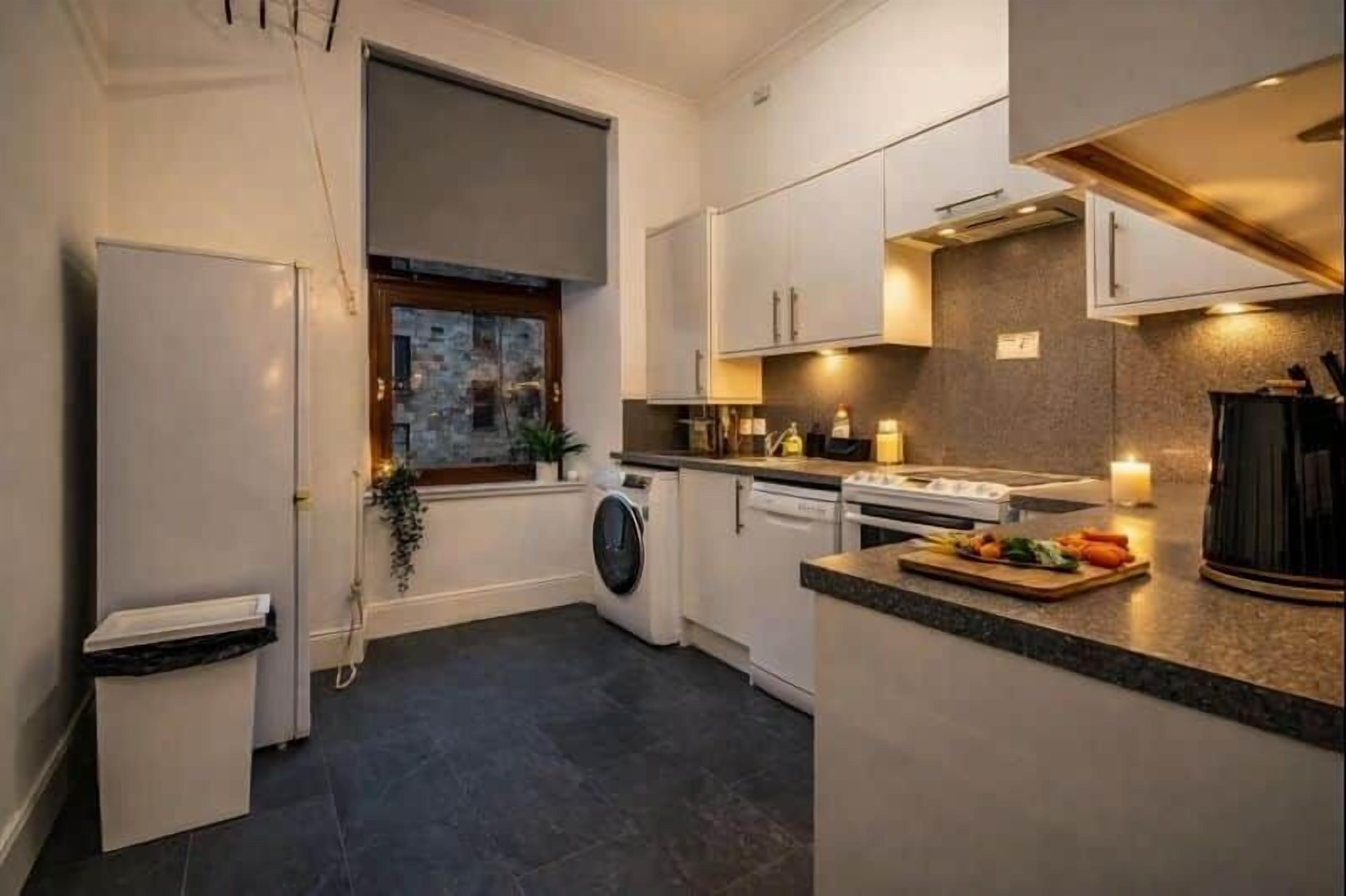 Una cocina moderna con lavadora y secadora integradas, un ventanal grande y una encimera con productos frescos.