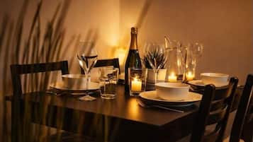 Una mesa lista para comer, con platos, vasos, una botella y velas.