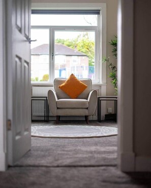 A room with a window, a chair with a cushion, a radiator, and a plant. - Reston 4 Bedroom House | 6 Double Beds|Sleeps 6 |Glasgow (Glasgow)