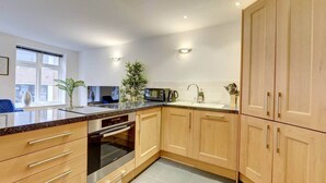 Una cocina moderna con armarios de madera, horno de acero inoxidable y encimera de granito.