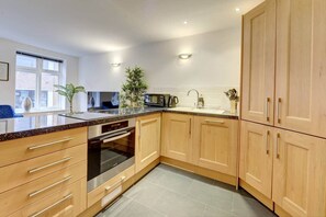 Eine moderne Küche mit Holzschränken, einem Edelstahlbackofen und einer Arbeitsplatte aus Granit.