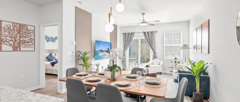 Un comedor moderno con una mesa de madera preparada para cuatro personas, rodeada de sillas grises.