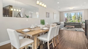 A modern dining area with a wooden table, white chairs, and a large mirror above.