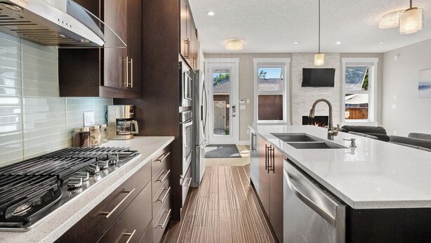 A modern kitchen with stainless steel appliances, a large island with a sink, and a view of the outdoors through the windows.