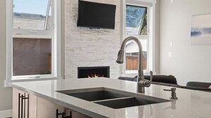 A modern kitchen with a large island, double sink, and a built-in fireplace.