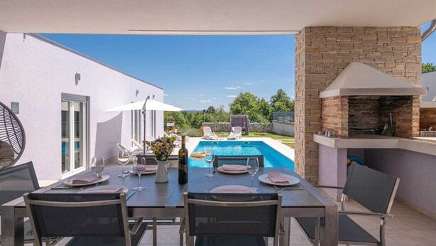 An outdoor dining area with a pool and a stone fireplace. - House Lavanda a relaxing retreat with court & sauna (Marići)