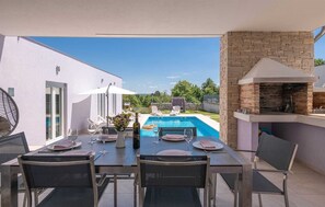 Un área de comedor al aire libre con piscina y chimenea de piedra.
