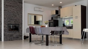 A modern kitchen with a stone accent wall, a dining area with a table and chairs, and a large mirror above the table. - House Lavanda a relaxing retreat with court & sauna (Marići)