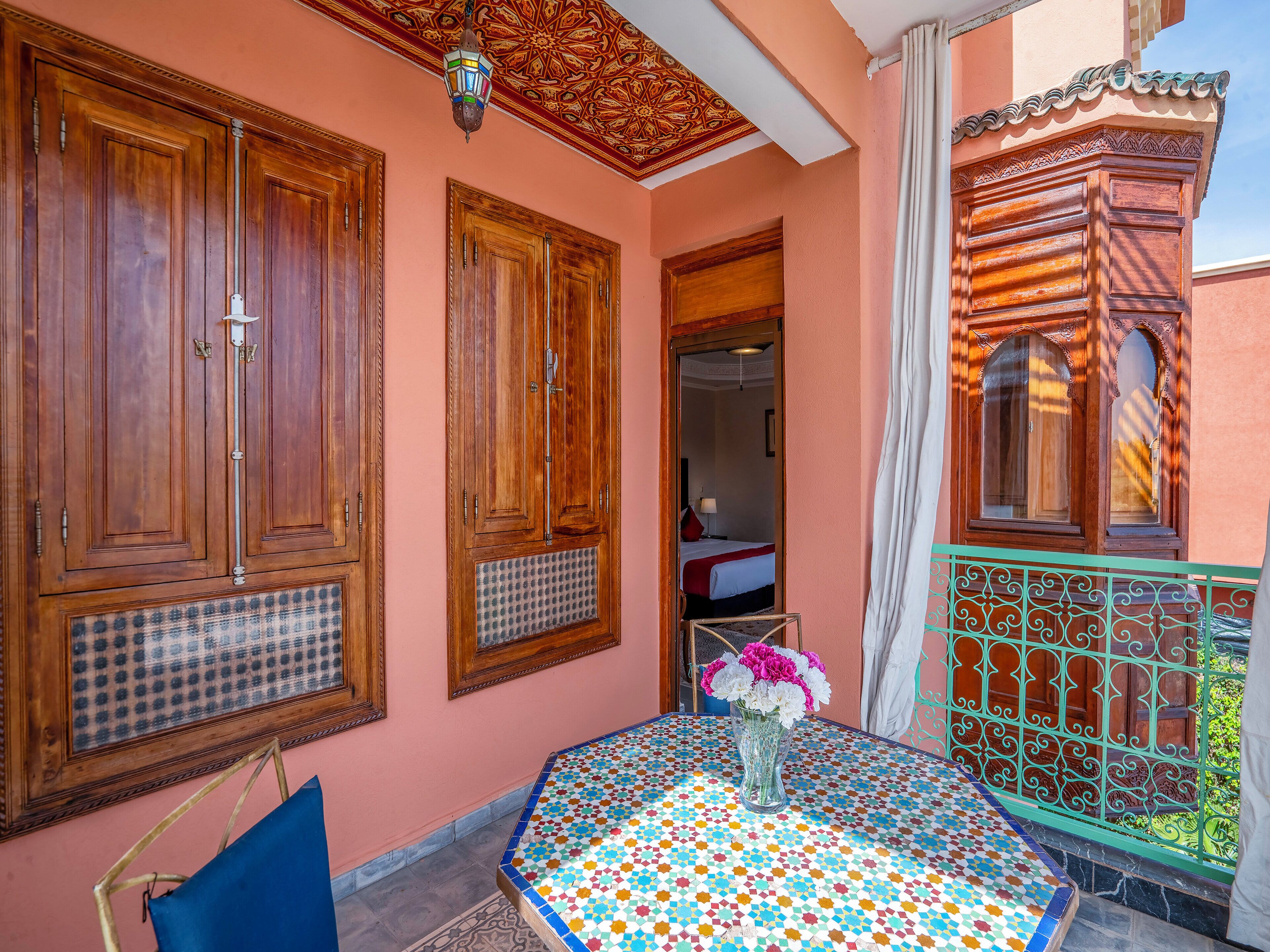 A room with wooden cabinets, a tiled table, and a balcony with a decorative railing.