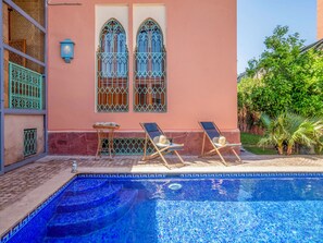 A swimming pool with two sun loungers and a small table with a hat.