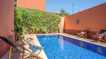 Una piscina al aire libre, sombrillas, tumbonas