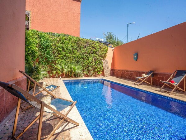 A swimming pool with clear blue water, surrounded by lounge chairs and a lush green hedge. - Hotel Boutique RAM Spa (Marrakech)