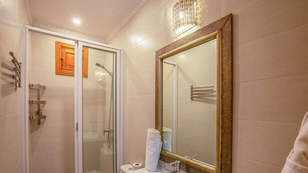 A bathroom with a glass-enclosed shower, a white sink with a glass bowl, and a large mirror with a decorative frame. - Hotel Boutique RAM Spa (Marrakech)