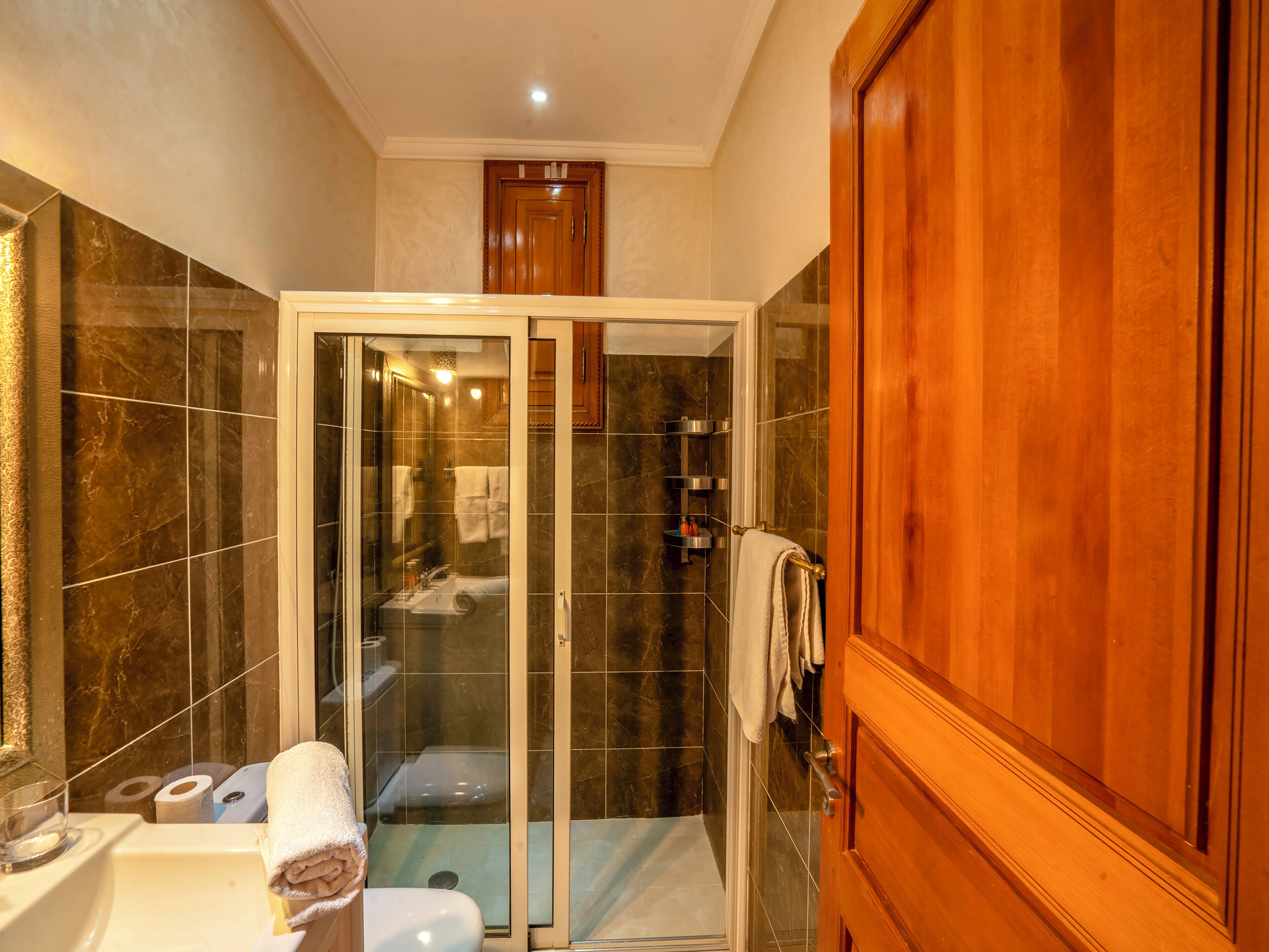 A bathroom with a glass-enclosed shower, a sink, and a toilet.