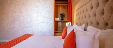 A hotel room with a large bed, a wooden wardrobe, and a red curtain.