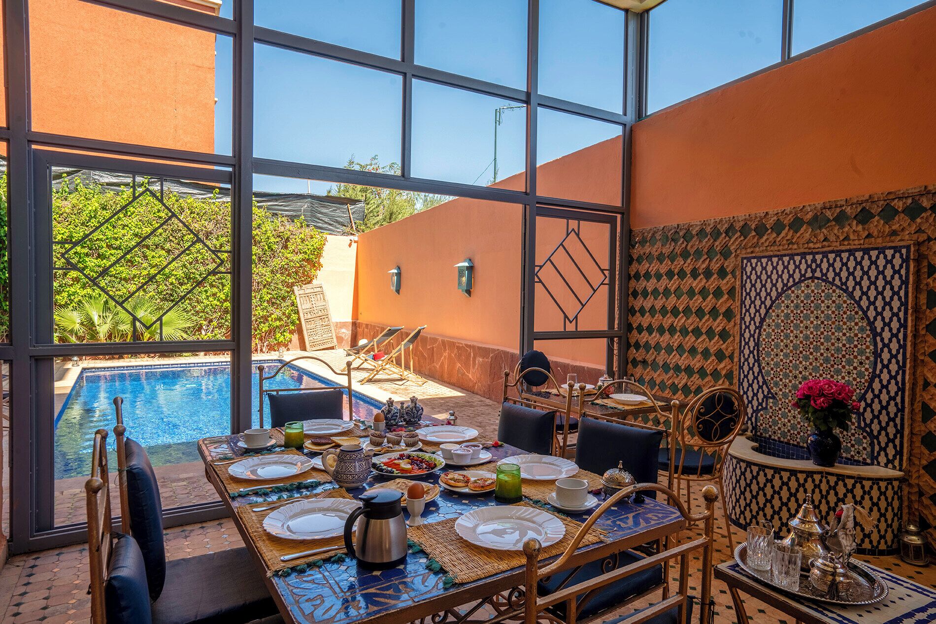 A dining area with a pool view, a table set for a meal, and a decorative wall.