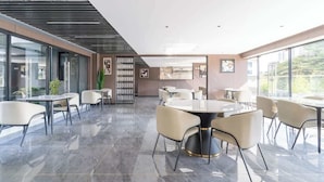Un espace intérieur moderne avec des murs en verre, une table ronde centrale et plusieurs coins salon.
