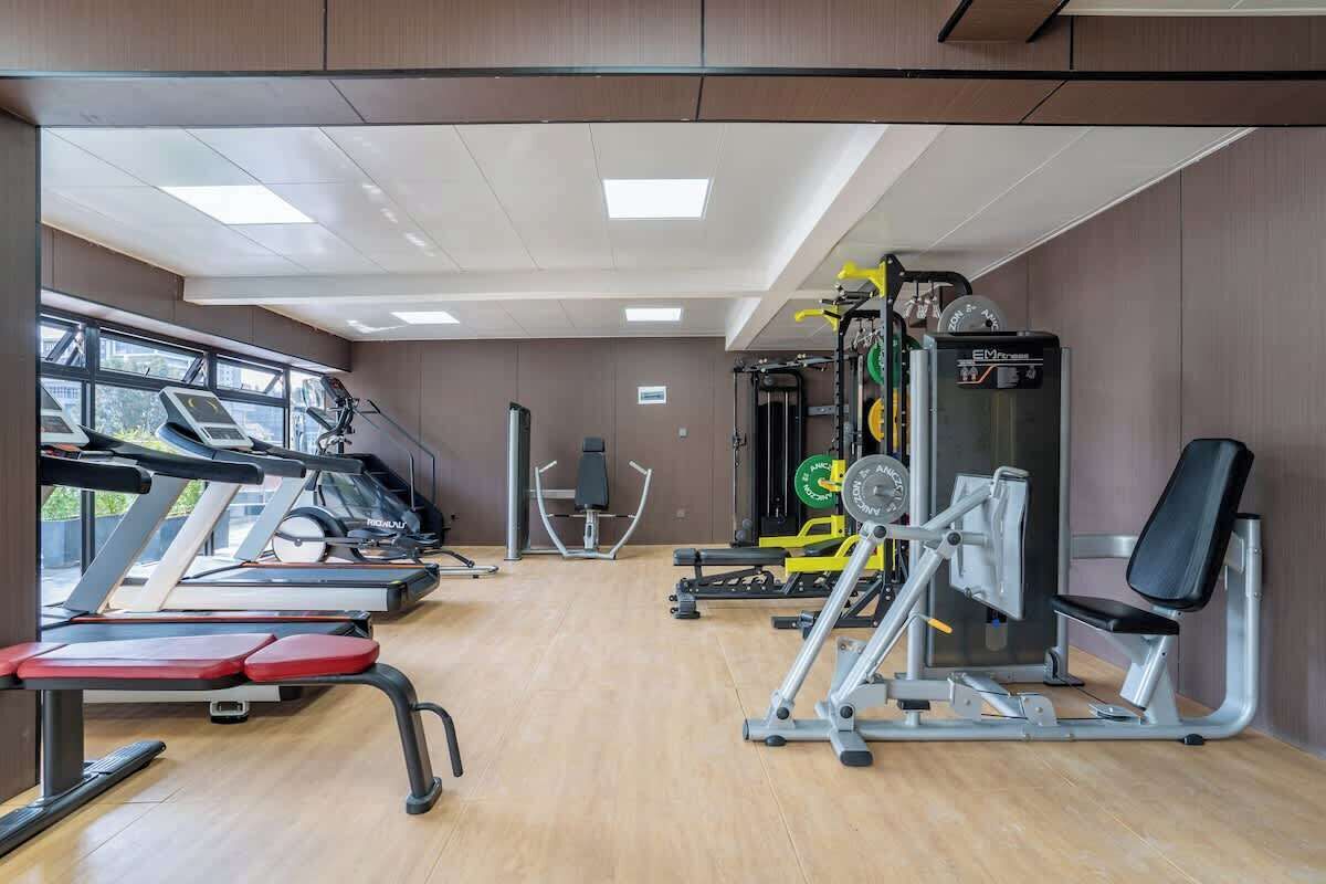Ein Fitnessstudio mit Laufbändern, Kraftgeräten und einer Bank.