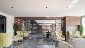 Un salon moderne avec un coin repas, comprenant une grande fenêtre, une cheminée et une cuisine en arrière-plan.