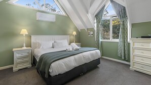 A bedroom with a skylight, a bed with white linens, a nightstand with a lamp, and a dresser. - Plum Retreat - Apollo Bay (Apollo Bay)