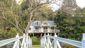 A wooden bridge leading to a house with a green roof, surrounded by trees and greenery. - Plum Retreat - Apollo Bay (Apollo Bay)