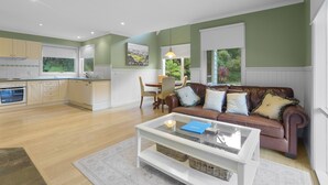 A spacious living area with a brown leather sofa, a glass coffee table, and a dining table with chairs. - Plum Retreat - Apollo Bay (Apollo Bay)