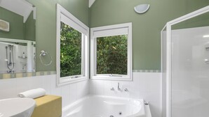 A bathroom with a large bathtub, a sink, and two windows with views of greenery. - Plum Retreat - Apollo Bay (Apollo Bay)