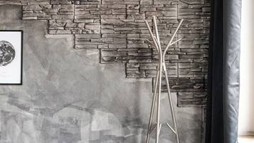 A room with a stone wall, a framed picture, a tall metal stand, and a dark-colored cabinet.