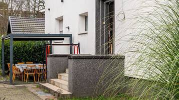 Een modern huis met een verharde oprit, een overdekt terras en een stenen muur.