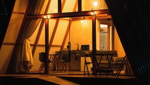 A cozy, triangular-roofed room with a dining table and chairs, a small kitchen area, and a visible door leading to another room. - Mont Hermon Hotel Castro (Castro)