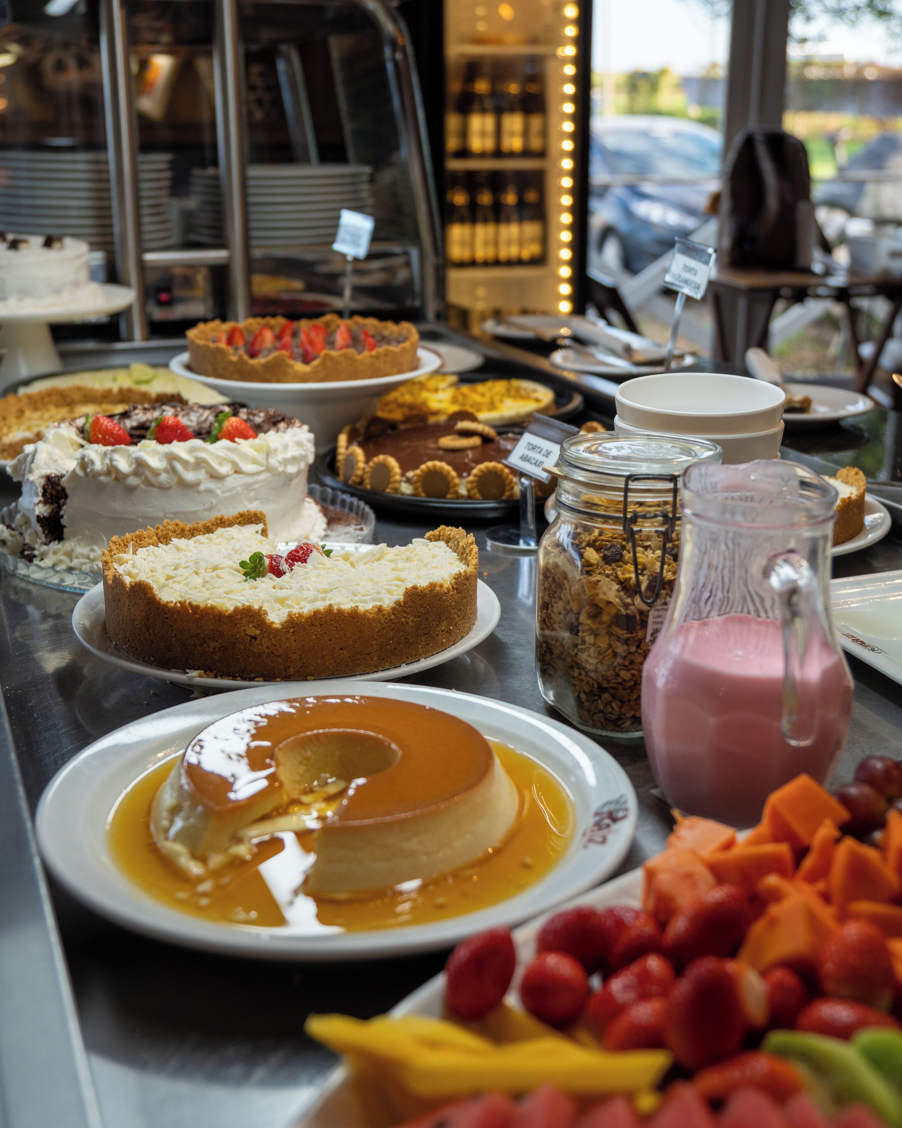 Una variedad de postres y frutas expuestas en una cafetería.