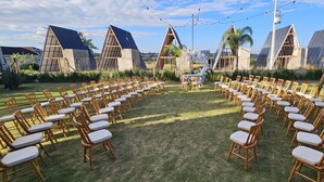 An outdoor seating area with rows of wooden chairs and tables, surrounded by modern buildings with solar panels. - Mont Hermon Hotel Castro (Castro)