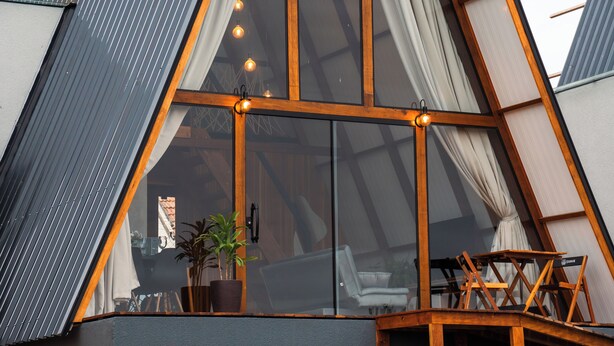 A modern building with a large glass window, wooden beams, and a potted plant. - Mont Hermon Hotel Castro (Castro)
