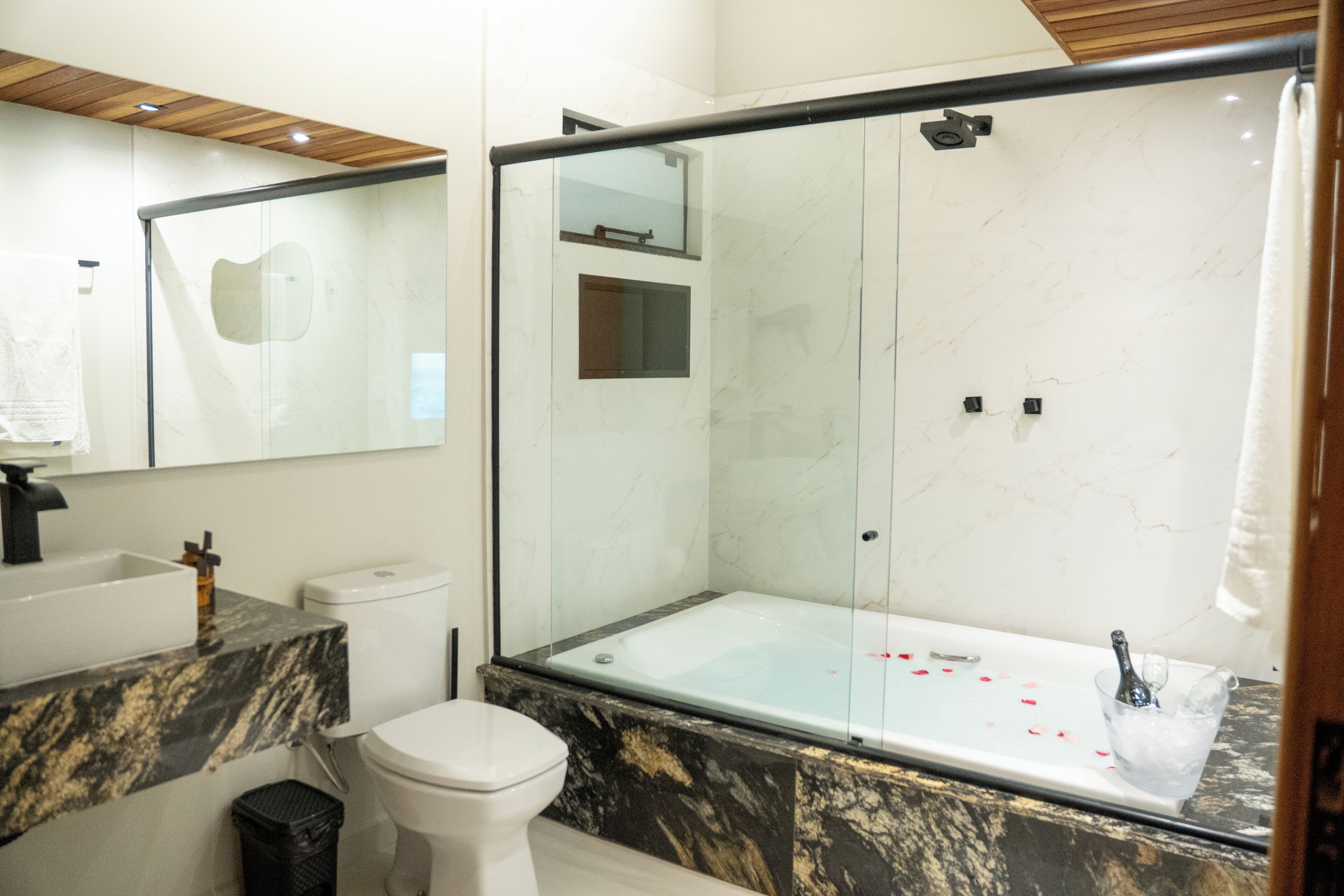 A modern bathroom with a glass-enclosed shower, a white toilet, and a marble countertop.