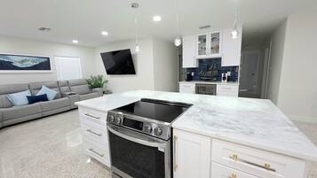 A modern kitchen with a built-in oven, white cabinetry, and a marble countertop.