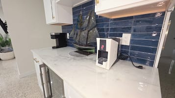 Cozinha com bancada de mármore, cafeteira e um modelo decorativo de navio.